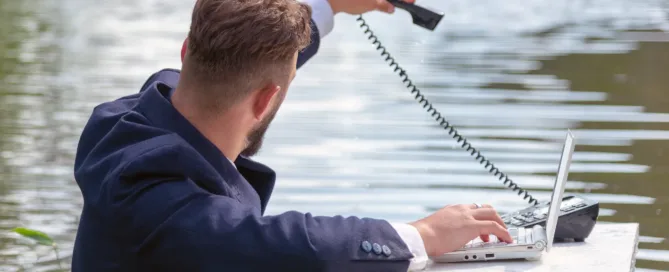 A working man looks stressed as he sits at a desk, surrounded by water
