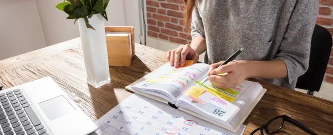 A women busy working at her desk, whilst planning her time using her calendar